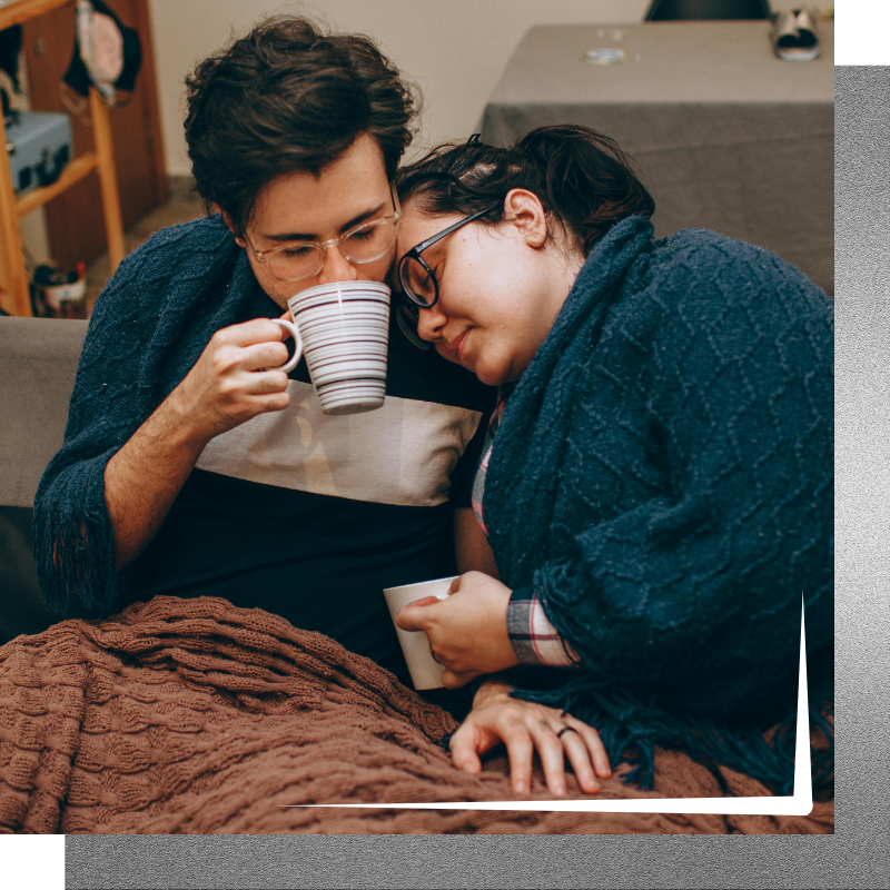 Couple bundled up together on a couch